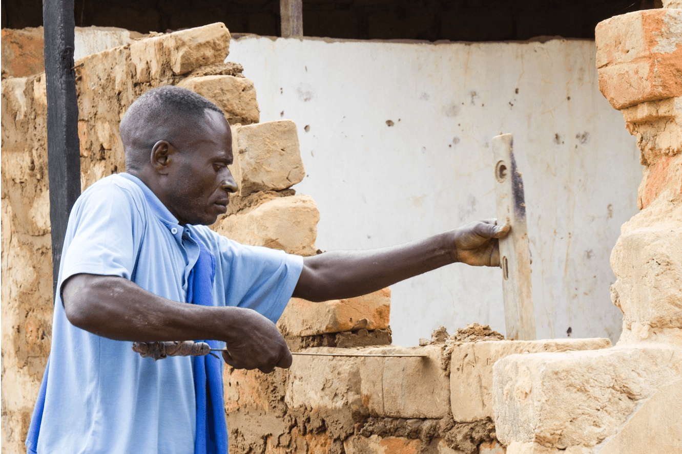 Photo d’un congolais en train de reconstruire sa maison après la guerre.